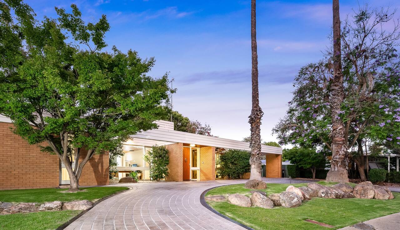 The lit front door of a mid-century brick home at dusk